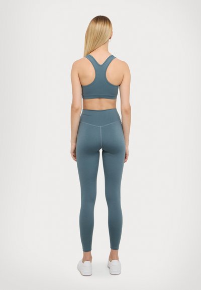 Sports bra and leggings set in teal, featuring a racerback design and high-waisted leggings with a smooth texture and minimal seams.