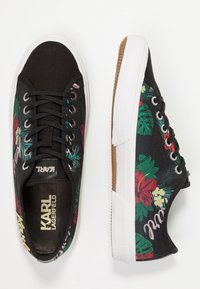 Mustat kangaskengät, joissa on kirkas punainen ja vihreä kukkakuosi, valkoinen kumipohja ja mustat nauhat; brändin nimi Karl Lagerfeld näkyy sisäpuolella ja kielessä.