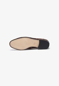 Suela de zapato de cuero marrón con un centro beige liso y tacón de goma negra. Presenta un borde cosido y un sutil diseño de estampado animal.