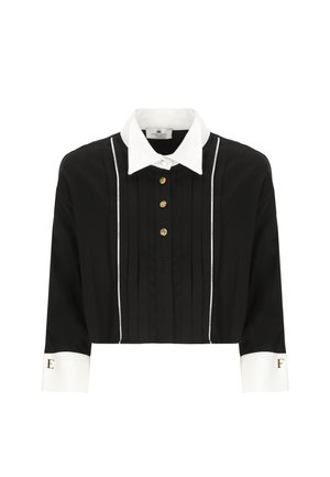 Camicetta nera cropped con colletto bianco, bottoni dorati e pieghe verticali. Presenta dettagli con strisce bianche e accenti del logo sulle maniche.