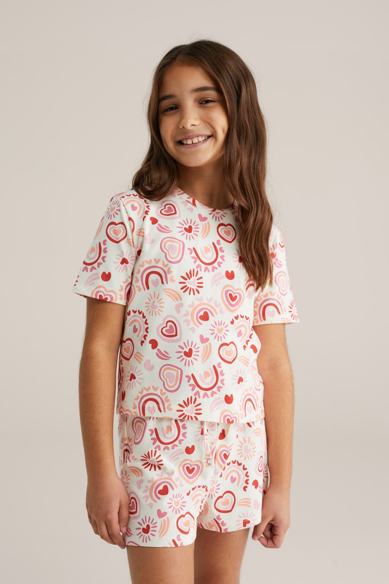 Ensemble en coton à manches courtes avec une base blanche ornée de motifs de cœurs roses et rouges ainsi que de soleils, composé d'un haut assorti à un short.