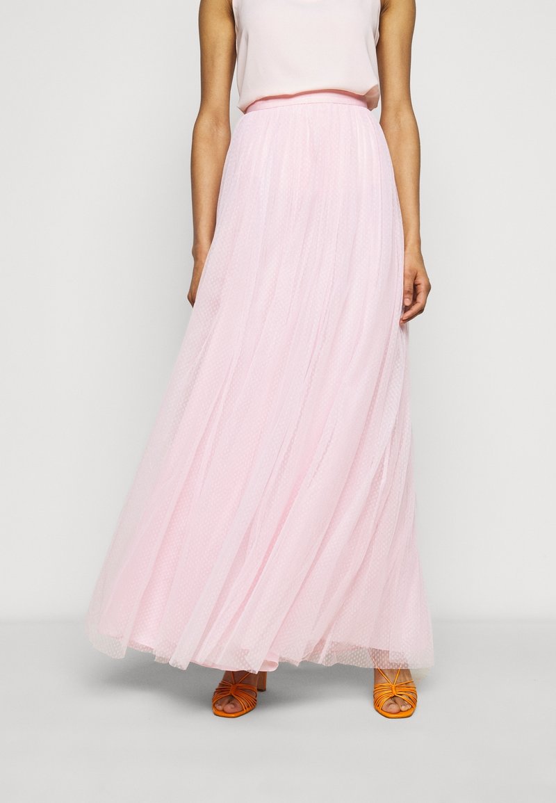 Rosa tyl maxi kjol med en strukturerad, lager-på-lager design. Har en figursydd midja och faller ner till golvet, i kombination med orangea remsandaler.