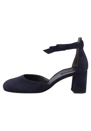 Escarpin en daim bleu marine avec un bout arrondi, une bride de cheville ornée d'un nœud et un talon épais. Texture lisse sans motifs visibles.