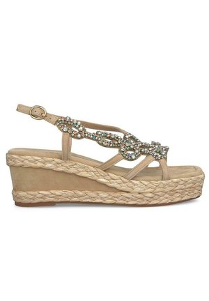 Beige wedge sandal with a braided jute platform, adorned with sparkling multi-colored gems on the strap. Adjustable ankle buckle closure.