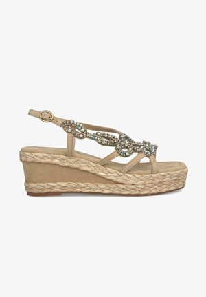 Sandale à talon compensé beige avec une plateforme en jute tressé, ornée de gemmes multicolores scintillantes sur la bride. Fermeture à boucle réglable au niveau de la cheville.