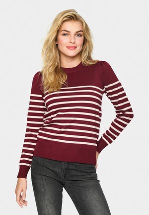 Pull en tricot bordeaux avec des rayures horizontales ivoire, col rond et manches côtelées. Présente une silhouette légèrement cintrée et un tissu texturé.