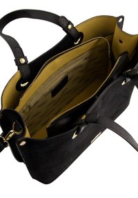 Sort ruskinds-håndtaske med læderdetaljer, en guld lynlås og et indre i sennepsfarve med flere lommer.