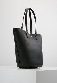 Zwarte lederen tote bag met een gestructureerde afwerking, rechte vorm, twee handvaten en gouden accenten op de basis en de straps.