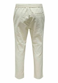 Lichtbeige katoenen broeken met een elastische tailleband, taps toelopend ontwerp en een enkele achterzak. Gladde, gestructureerde stof met minimale details.