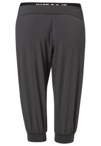 Pantaloni sportivi neri con una superficie liscia, vita elastica con la scritta "JUST DO IT" e polsini aderenti alle caviglie.