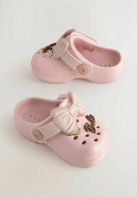 Roosa plastist sabad, millel on vormitud pael ning dekoratiivne ehe, ventilatsiooniaugud ja tekstureeritud tallad tugevama haarde saavutamiseks.