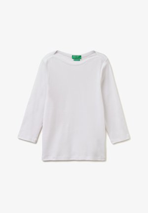 Jednoduché bílé tričko s dlouhým rukávem a výstřihem do člunu, se zelenou nášivkou s nápisem "United Colors of Benetton" na bílém pozadí.