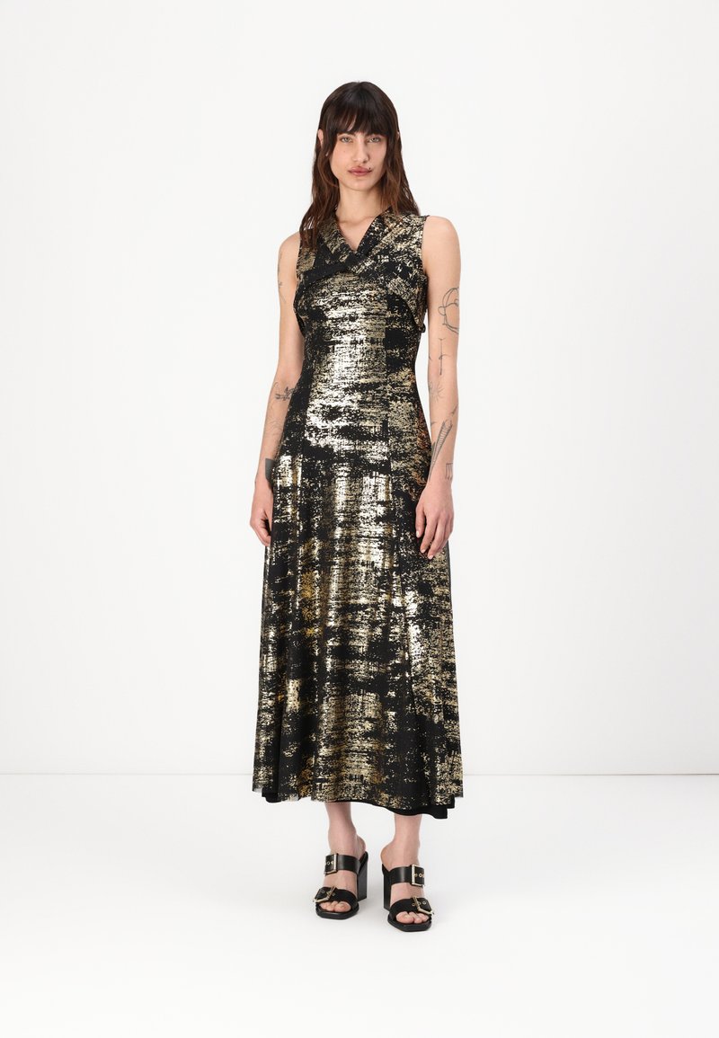Rochie cu paiete negre și aurii, cu un corset ajustat și fustă evazată; prezintă un decolteu în V și un design fără mâneci. Sandale negre cu toc.