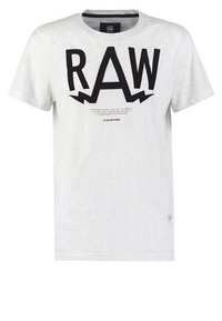 Světlé šedé tričko vyrobené z bavlny, s výrazným černým grafickým designem "RAW" a motivy blesků, s malým textem níže. Kulatý výstřih, krátké rukávy.