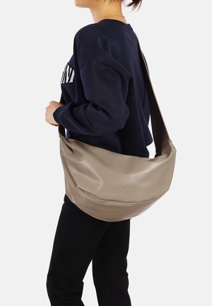 Borsa hobo in pelle beige con una texture liscia e un design morbido, dotata di una lunga tracolla e un piccolo logo vicino alla parte inferiore.