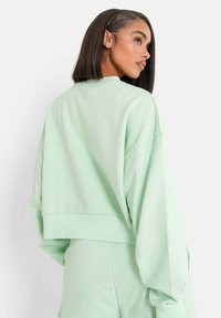 Lichtgroene cropped sweatshirt met oversized mouwen en een relaxte pasvorm. Zachte stof met een minimalistisch ontwerp, zonder zichtbare logo's.