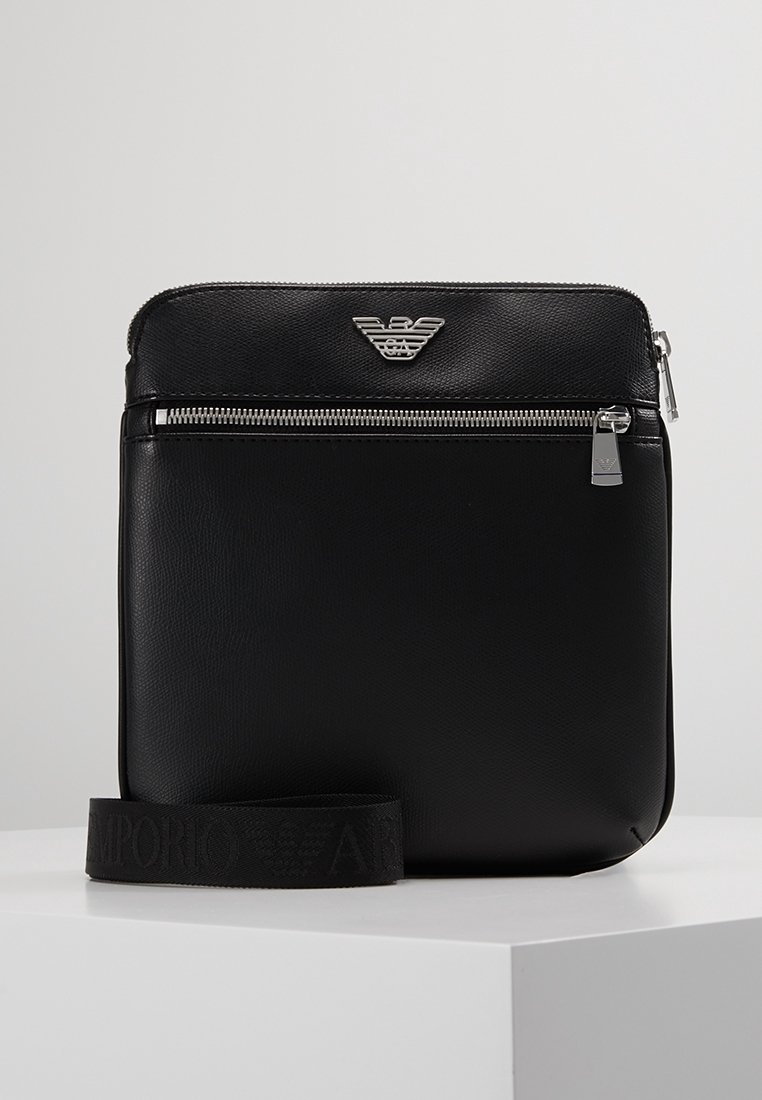Borsa a tracolla in pelle nera con logo argentato, chiusura con zip e superficie testurizzata. Include una tracolla regolabile abbinata.