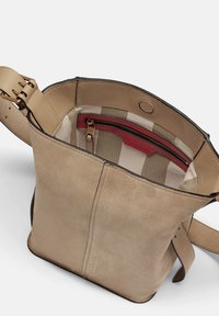 Borsa a mano in suede beige con una forma strutturata, rifiniture in pelle e un interno con fodera a righe e una tasca con zip rossa.