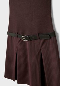 Bordeaux jurk met een aangesloten bovenstuk en een geplooide rok. Heeft een zwarte riem met een zilveren gesp en subtiele verticale streepjes op de rok.
