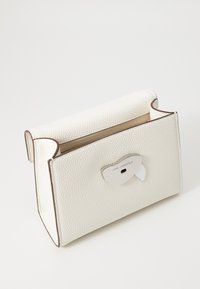Borsa a mano in pelle bianca texturizzata con forma strutturata, rifiniture in marrone, chiusura magnetica e accento in argento del logo sulla parte anteriore.
