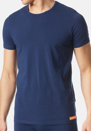 T-shirt à manches courtes bleu marine en coton doux avec un col rond et une petite étiquette orange au bas. Ajusté près du corps.