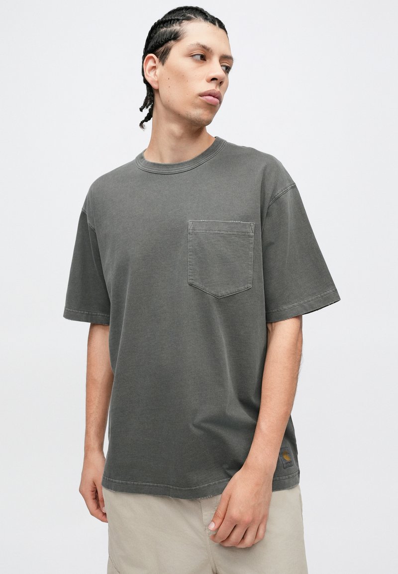 Grå bomullst-shirt med korta ärmar, rund halsringning och en bröstficka. Har en avslappnad passform och minimala sömdetaljer.