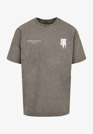 Grå oversize t-shirt lavet af bomuld med en falmet tekstur. Har et hvidt logo print på brystet og subtil tekst under det. Korte ærmer.
