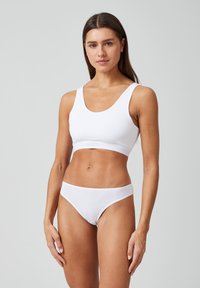 Witte katoenen sportbeha met brede schouderbanden en een ondersteunende band. Gecombineerd met bijpassende low-rise bikini slipjes. Glad textuur, minimalistisch ontwerp.