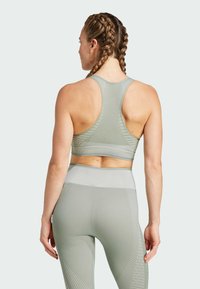 Ljusgrön sportig crop top med racerback-design, ribbat mönster och matchande högmidjade leggings med diagonala mönster.