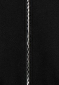 Veste noire zippée avec une texture de tissu lisse, dotée d'une fermeture éclair métallique argentée au centre.