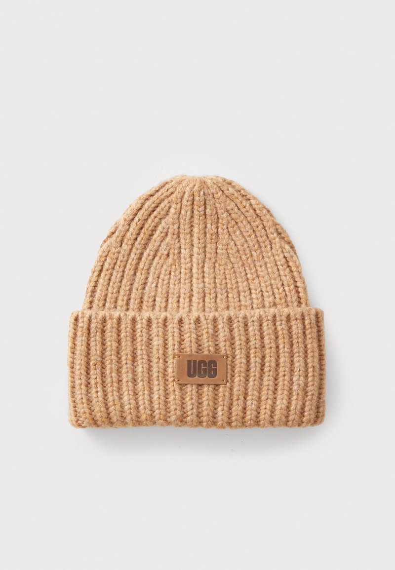 Bonnet tricoté en brun clair avec une texture côtelée et un revers replié. Présente un petit patch en tan avec le logo UGG rectangulaire.