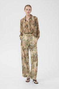 Completo blusa e pantaloni con motivo marrone e beige, realizzato in tessuto leggero con design a stampa animalier. Caratterizzato da una vestibilità comoda e tasche.