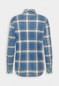 Chemise à manches longues à carreaux bleu et blanc avec poignets boutonnés, vue de dos sur un fond gris clair uni.