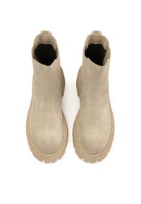 Paire de bottines beiges en daim avec semelles épaisses en caoutchouc et languettes, vue de dessus sur fond blanc.