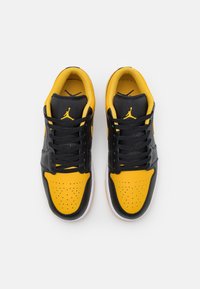 Svarta och gula låga sneakers med läderöverkänsla, perforerat tåparti, svarta snören och vit gummi sula med logotypdetaljer.