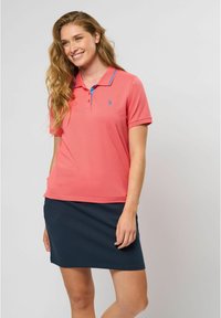 Roza polo majica s plavim akcentima, kratkim rukavima i malim logom. Uparena s tamnoplavom suknjom, nudi opušten izgled u sportskom stilu.