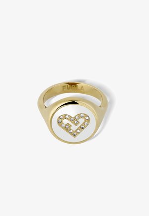 Złoty pierścionek z okrągłym białym emaliowym środkiem, ozdobionym sercem z przejrzystymi kryształami; wygrawerowana nazwa marki w środku.