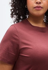 Κοντομάνικο μπλουζάκι βυσσινί από απαλό βαμβάκι. Διαθέτει κλασικό στρογγυλό λαιμόκοψη και άνετη εφαρμογή με λεπτομέρειες διακριτικής ραφής.