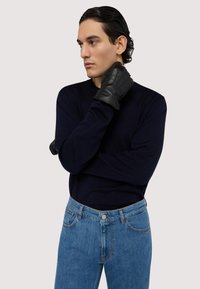 Námořnický svetr s dlouhým rukávem, v kombinaci s světle modrými džíny. Černé kožené rukavice dotvářejí vzhled. Jednoduchý design, bez vzorů.