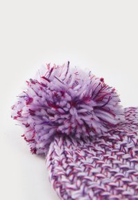 Violetinis mezgamas kepurė su tekstūruotu raštu. Papuošta pūkuotu violetiniu pom-pomu su raudonomis gijomis. Minkšta, jauki medžiaga.