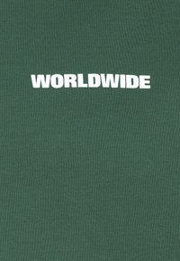 Groene katoenen T-shirt met het woord "WORLDWIDE" in vetgedrukte witte letters over de borst. Soepele textuur, getailleerd ontwerp.
