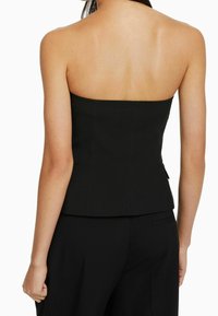 Černý top bez ramínek s těsným střihem, hladkou texturou a peplum lemem. Vyznačuje se čistým, upraveným siluetem bez viditelného kovu.