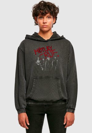 Čierna grafická mikina s kapucňou a predným vreckom, na ktorej je červený nápis "MÖTLEY CRÜE" a jemne zafarbený obraz skupiny. Mäkká textúra s dlhými rukávmi.