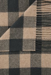 Wollen sjaal met een zwart en beige ruitpatroon. Heeft franjes aan de randen en een zachte textuur met afwisselend gecontroleerde vierkanten.