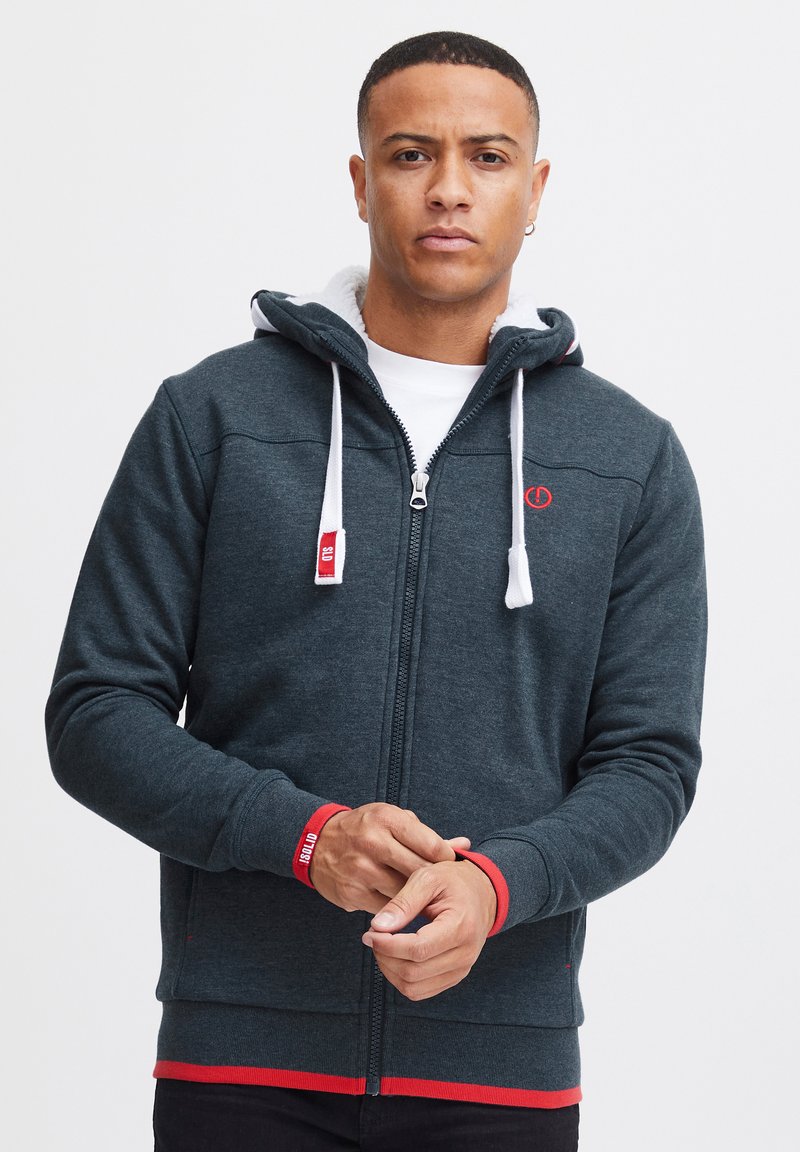 Dunkelgrauer Zip-Hoodie mit weißen Kordeln und roten Akzenten an den Bündchen und am Saum. Verfügt über ein weiches Innenfutter und ein Logodetail.