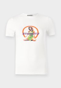 Hvit bomulls T-skjorte med grafisk trykk av en sittende kvinne i en grønn kjole, omringet av en oransje sirkel og lilla tekst.