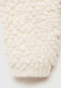 Strukturierter cremefarbener Strickstoff mit einem Noppenmuster, ausgestattet mit einem gerippten Bund und einem weichen, flauschigen Aussehen.