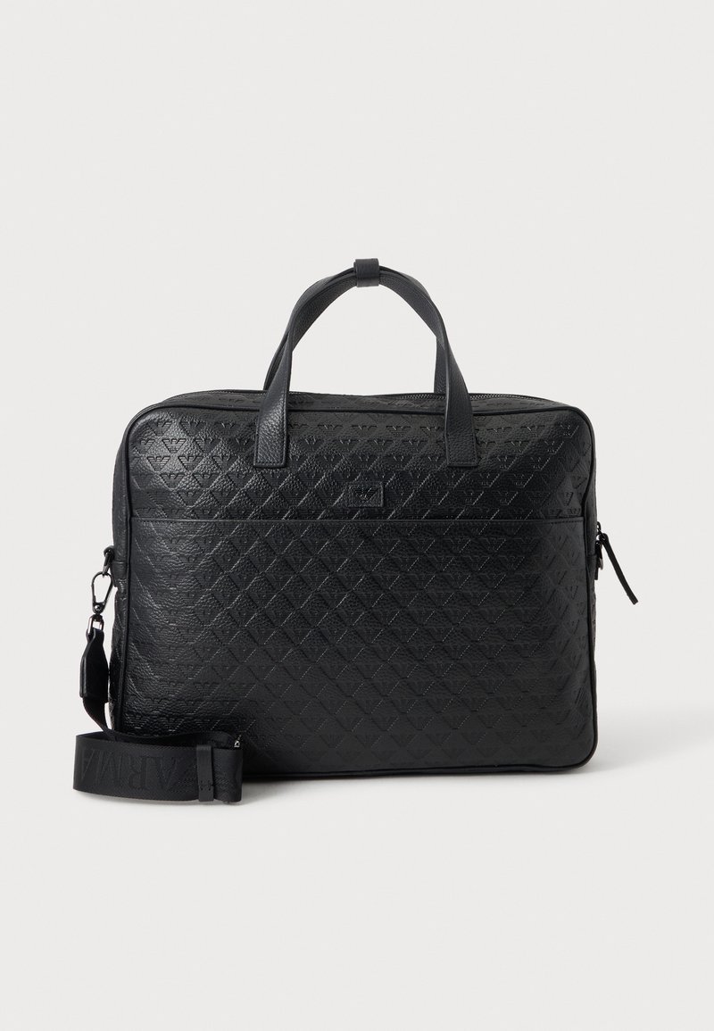 Serviette en cuir noir avec motif diamant embossé, poignées supérieures et bandoulière amovible sur un fond uni.