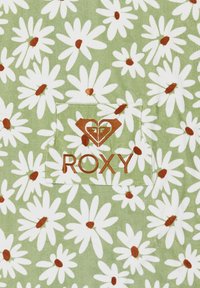 Grüner Stoff mit weißen Gänseblümchen und braunen Mittelpunkten sowie einer genähten Tasche mit einem braunen Roxy-Logo und -Text.
