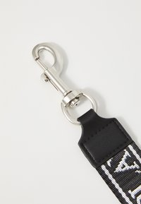 Black and white fabric strap with a metal clip, featuring a textured leather accent and circular ring for attachment.
